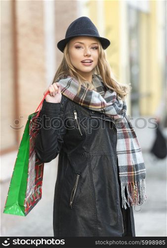 Pretty girl , outside for winter shopping , she have scarf hat and shopping bag , she looks in camera smiling