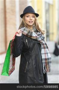 Pretty girl , outside for winter shopping , she have scarf hat and shopping bag , she looks in camera smiling