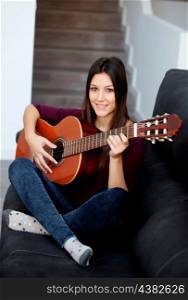 Pretty girl playing guitar on the couch at home
