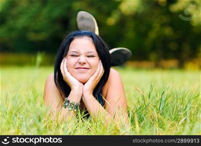 Pretty girl relaxing outdoor on green grass and making funny face