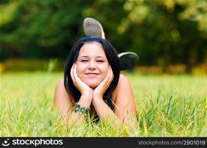 Pretty girl relaxing outdoor on green grass and making funny face