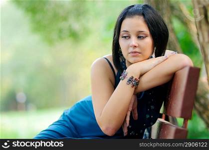 Pretty girl siiting on a bench in a park and thinking