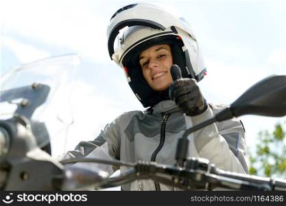 pretty girl sits on a motorcycle and has a helmet on his head
