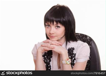Pretty girl sitting in a call center with a laptop in a white blouse with black embroidery. Portrait of call-center employee in a chair