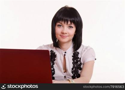 Pretty girl sitting in a call center with a laptop in a white blouse with black embroidery. Portrait of a smiling employee call-center front the monitor