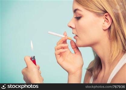 Pretty girl smoking cigarette using lighter. Addicted nicotine problems in young age. Addiction concept.. Girl using lighter to light cigarette.