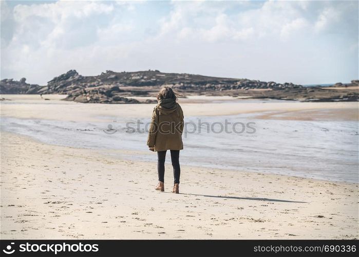 pretty girl walking on the shore of the sea at the Tregastel, normandy. France