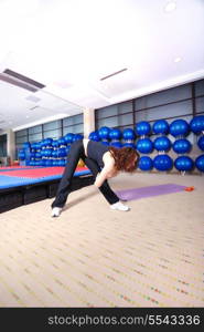 pretty girl warming up andd streching in fitness studio