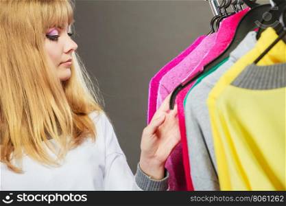 Pretty girl watching new clothes.. Pretty happy woman watching clothing from new collection wardrobe. Young undecided shopper girl choosing which clothes to wear. Shopping sale concept.