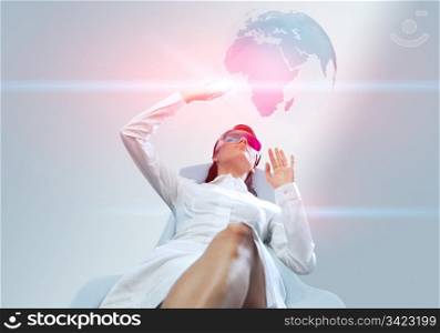Pretty girl wearing 3d anaglyph stereo glasses. Operating futuristic 3d interface. Touching three-dimensional globe. One of a series.