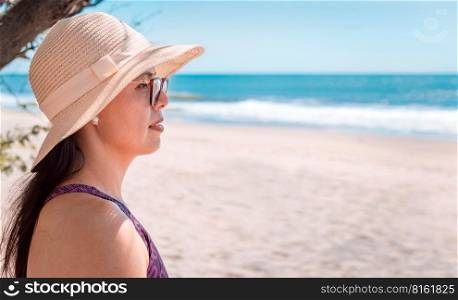 Pretty girl with a hat looking at the sea, close up of a woman looking at the ocean.