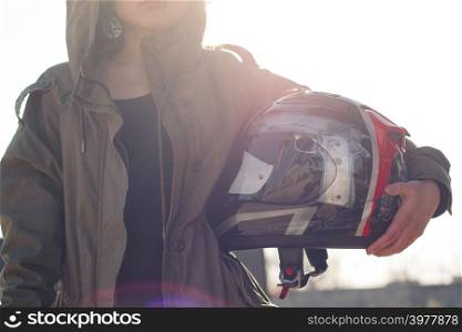 Pretty girl with custom motorcycle helmet in hands with sunbright background
