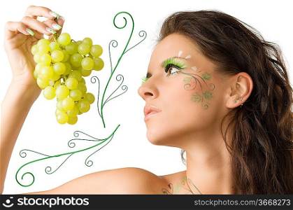 pretty girl with face painted looking at the green grape kept in her hand
