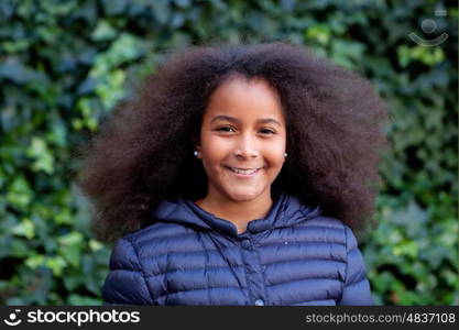 Pretty girl with long afro hair in the garden with a blue coat