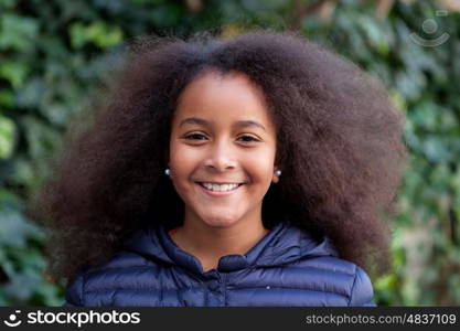 Pretty girl with long afro hair in the garden with a blue coat