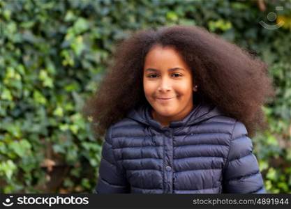 Pretty girl with long afro hair in the garden with a blue coat