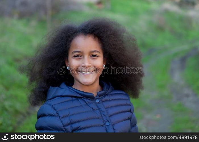 Pretty girl with long afro hair in the garden with a blue coat