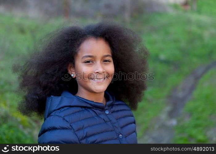 Pretty girl with long afro hair in the garden with a blue coat