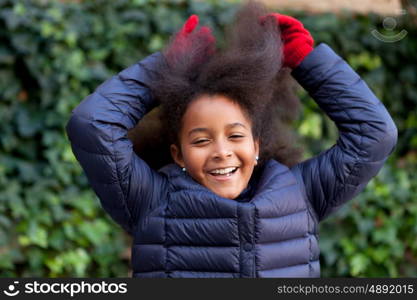 Pretty girl with long afro hair in the garden with a blue coat