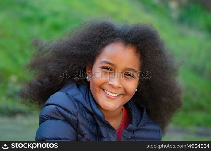 Pretty girl with long afro hair in the garden with a blue coat