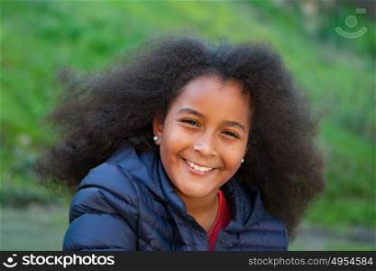 Pretty girl with long afro hair in the garden with a blue coat