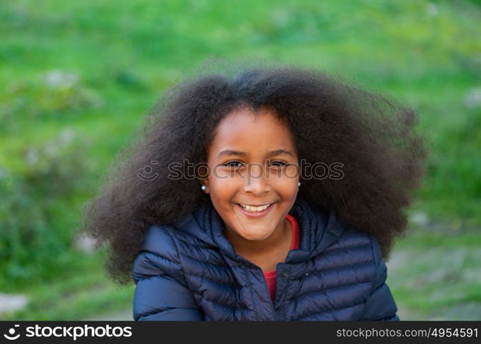 Pretty girl with long afro hair in the garden with a blue coat