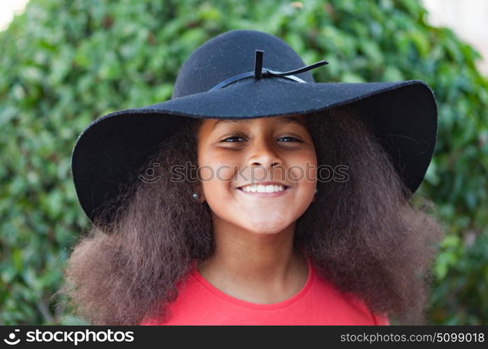 Pretty girl with long afro hair in the garden with a elegant black hat