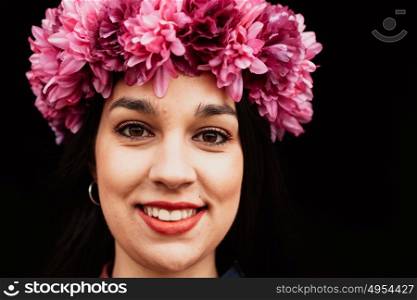 Pretty girl with pink flower crown in her head and a black background
