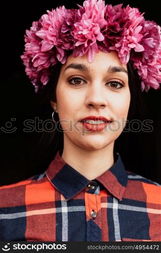 Pretty girl with pink flower crown in her head and a black background