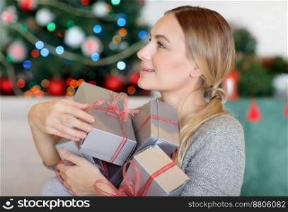 Pretty girl with pleasure receiving Christmas gifts, spending happy time at home in winter holidays. Receiving Christmas gifts