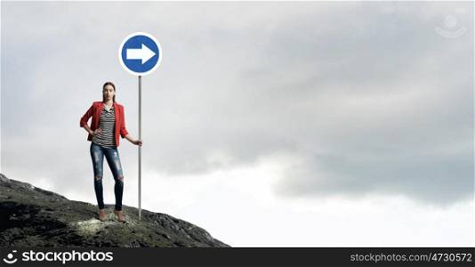 Pretty girl with roadsign. Young girl in red jacket in room showing roadsign