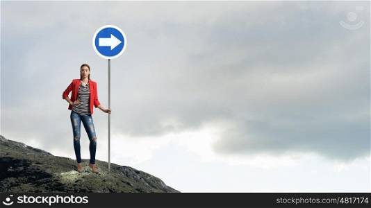 Pretty girl with roadsign. Young girl in red jacket in room showing roadsign