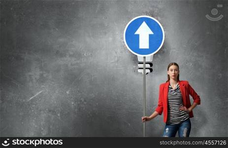 Pretty girl with roadsign. Young woman in red jacket holding road sign