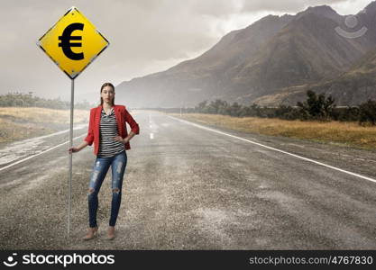 Pretty girl with roadsign. Young woman in red jacket holding yellow road sign