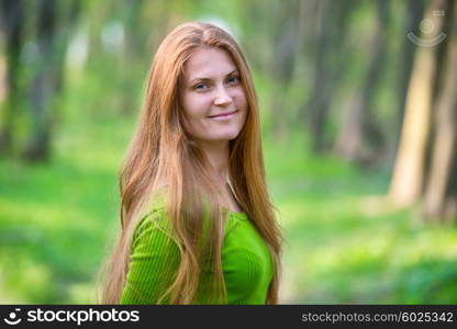 Pretty happy woman with red long hair in the green spring park