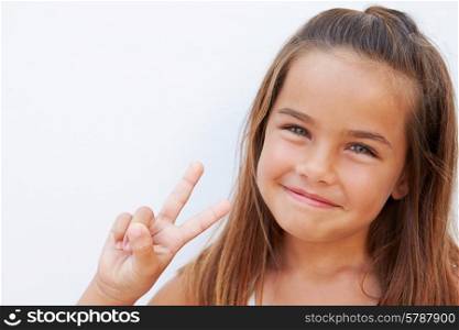 Pretty Hispanic Girl Standing By Wall Making Peace Sign