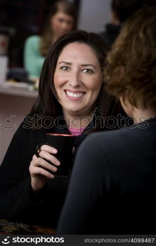 Pretty Hispanic woman in cafe with cup of coffee or tea