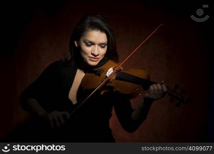Pretty Hispanic woman in studio playing a violin