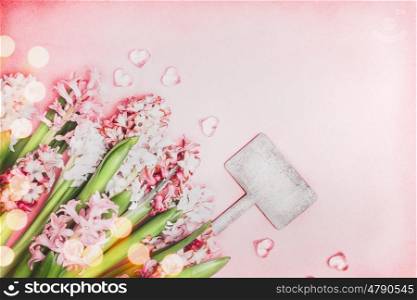 Pretty Hyacinths flowers with bokeh and hearts and blank wooden sign on pink background, top view