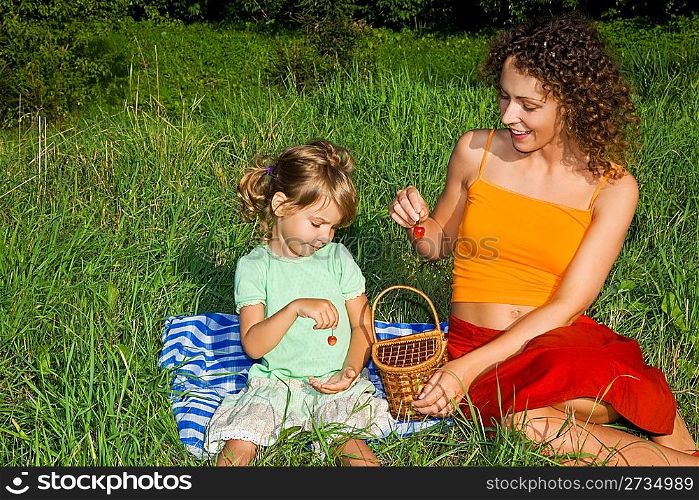 pretty Little Girl and Young Women keeps in hand sweet cherries on picnic