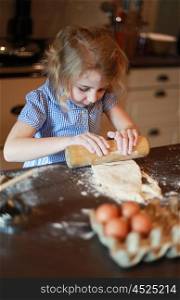 Pretty little girl concentrating on rolling out pastry