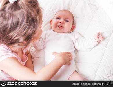 Pretty little girl laying with her adorable brother on the soft background. Sister with brother