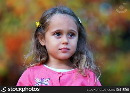 Pretty little girl with big eyes looking seriously, outdoor