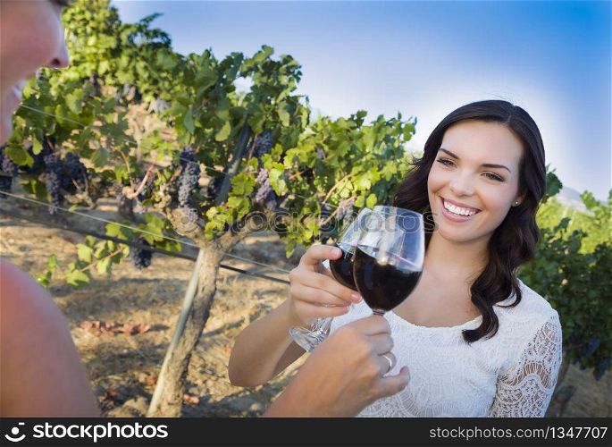 Pretty Mixed Race Young Adult Woman Enjoying A Glass of Wine in the Vineyard with Friends.