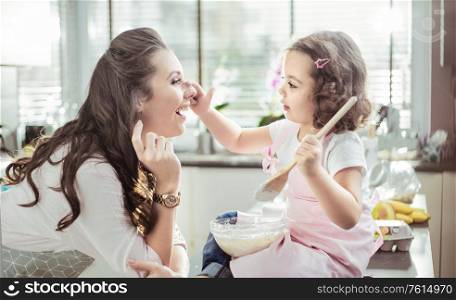 Pretty mother and her little daughter preparing a cake