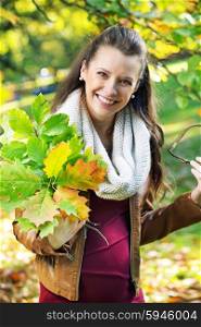 Pretty mother holding bouquet of autumn leaves