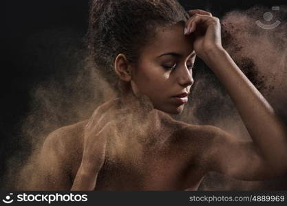 Pretty mulatto woman sprinkling a sand