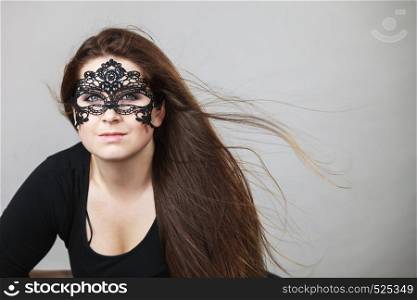Pretty mysterious woman wearing black eye lace mask having tousled windblown long brown hair.. Mysterious woman wearing lace mask