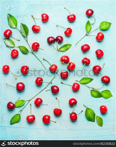 Pretty pattern made of sweet cherry with green leaves on light blue shabby chic background, top view