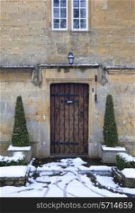 Pretty period property doorway with topiary box trees and snow, Broadway, Worcestershire, England.